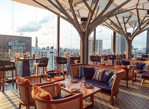 The greenery-filled Above Eleven rooftop garden lit up at night over Sukhumvit, Bangkok
