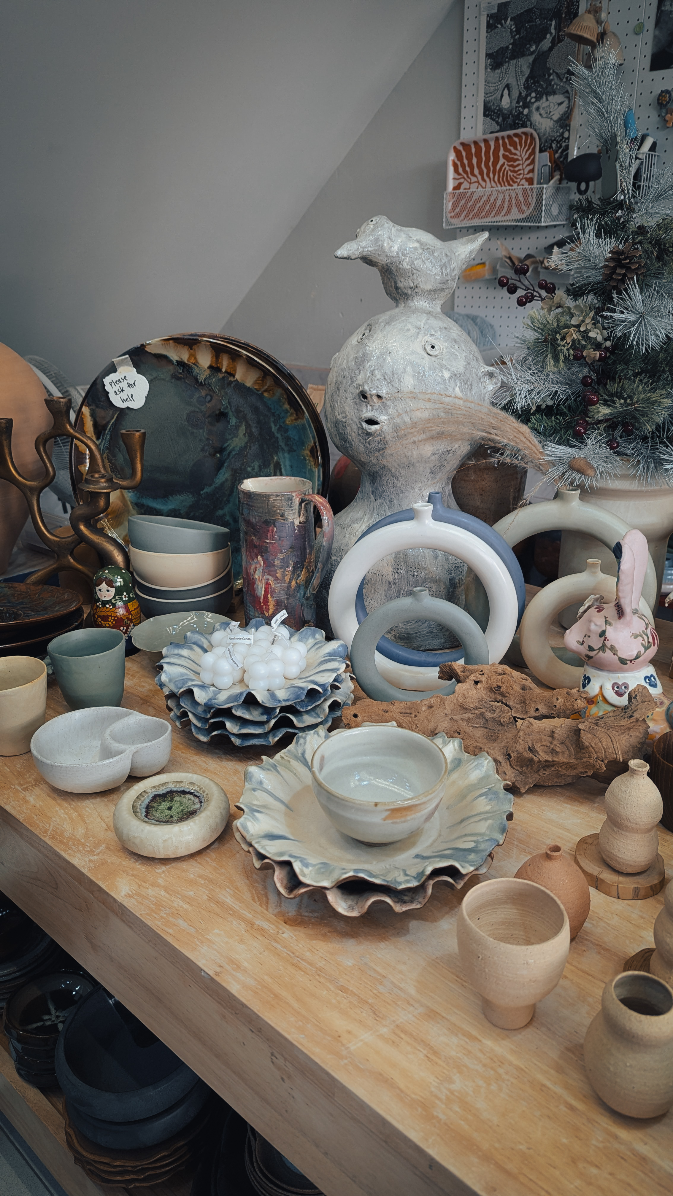 A table of handmade Thai ceramics: ruffled bowls, ring vases, cups, and glazed plates in a craft shop