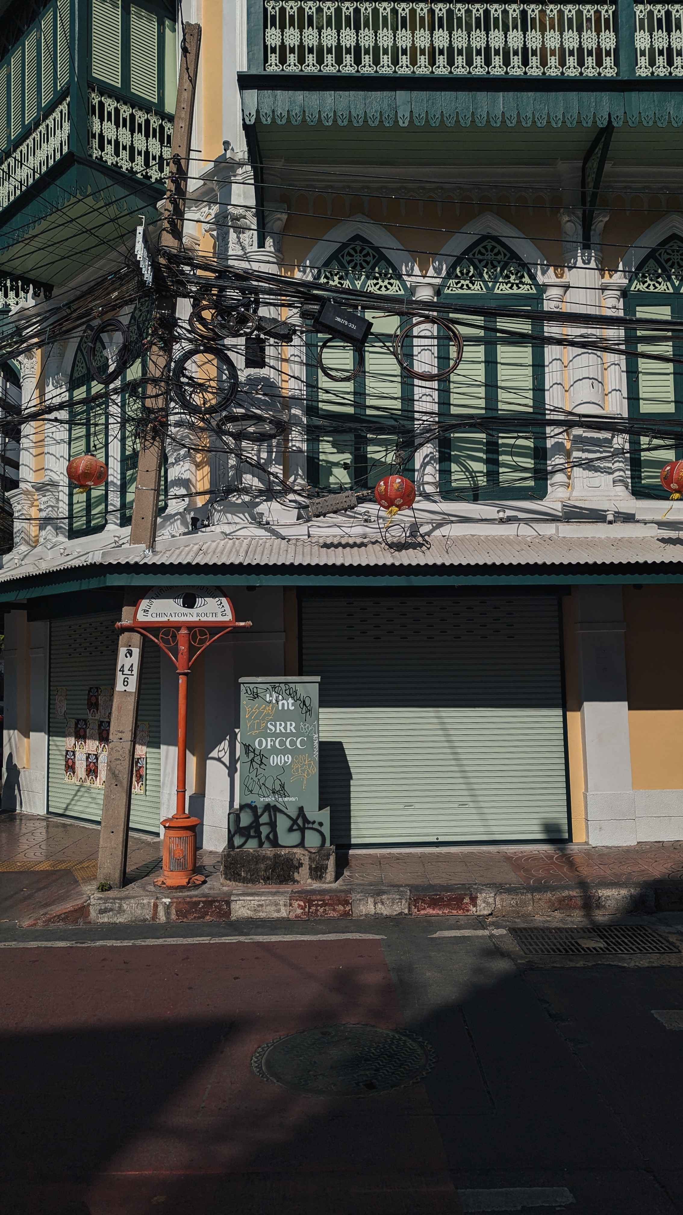 A restored Sino-Portuguese shophouse with green louvered shutters and red lanterns on the Chinatown Route, Bangkok