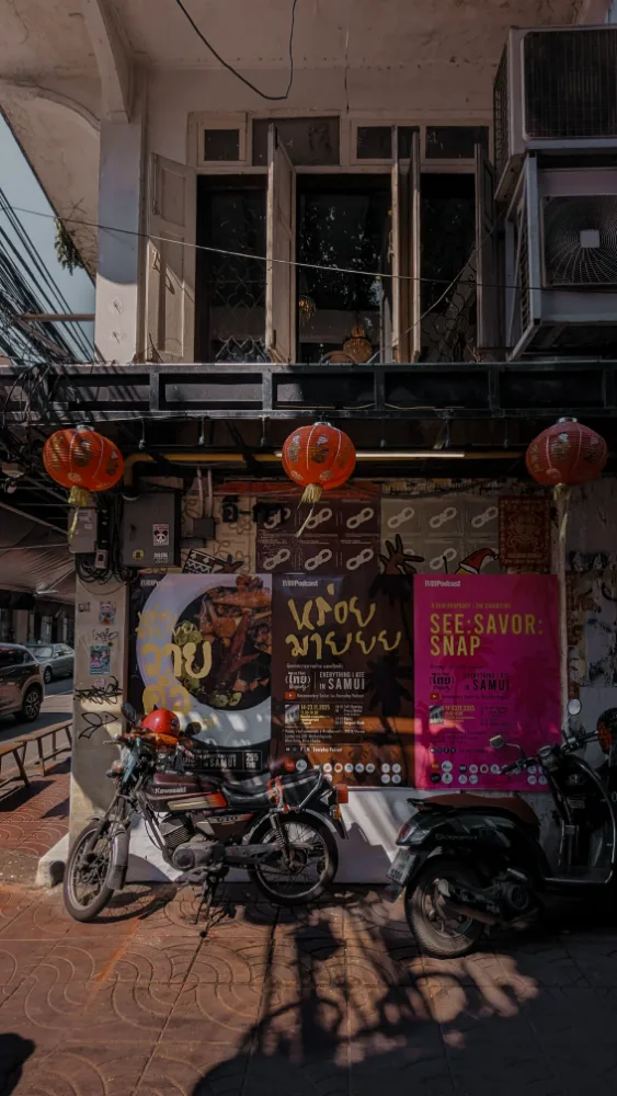 An old Chinatown shophouse wall pasted with EIRD Podcast exhibition pop-up posters and hung with red lanterns