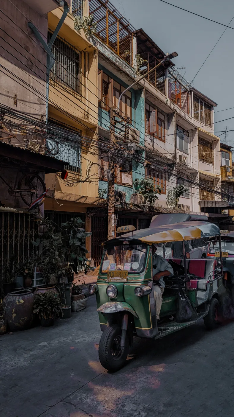 Tuk-tuks lined up on a busy Bangkok street