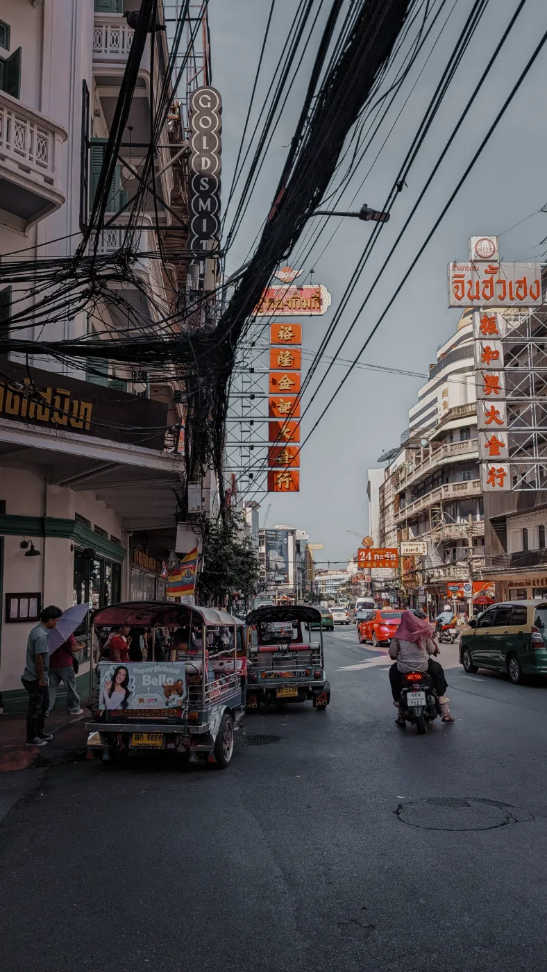 Vertical neon gold-shop signs in Chinese and Thai script over tuk-tuks on Yaowarat Road, Bangkok’s Chinatown