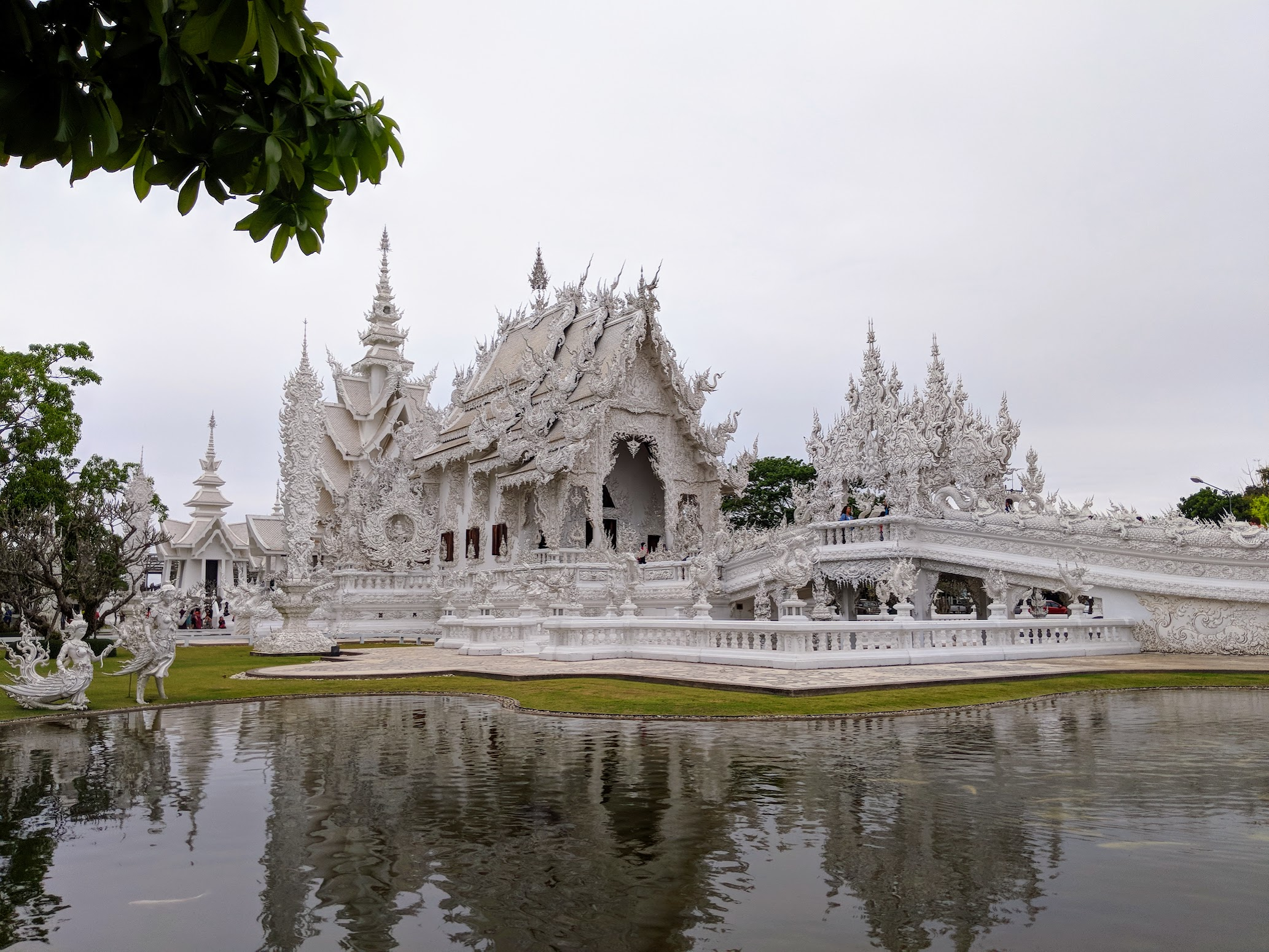 The all-white, mirror-flecked Wat Rong Khun (White Temple) in Chiang Rai, reflected in its pond