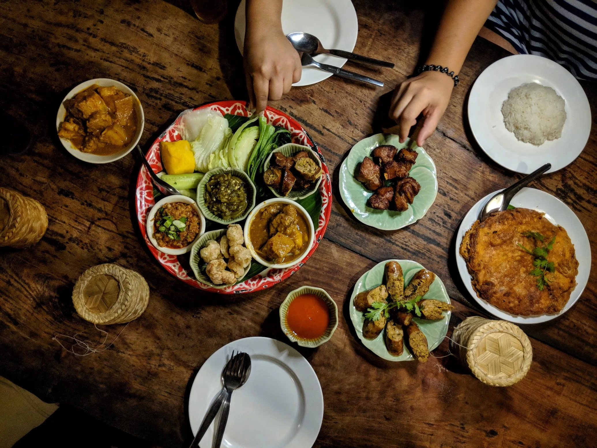 A khantoke spread of northern dishes with two baskets of sticky rice
