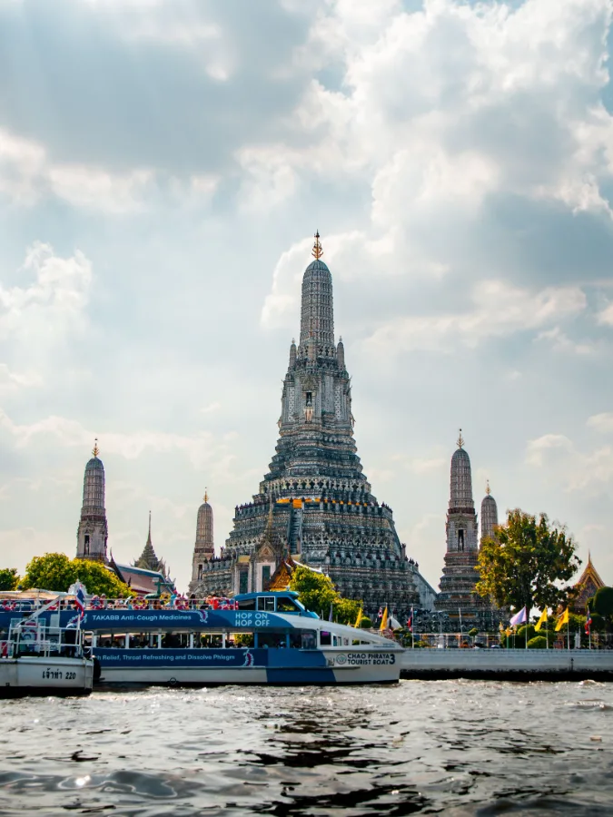 Wat Arun temple with tourist boats on the Chao Phraya River, Bangkok