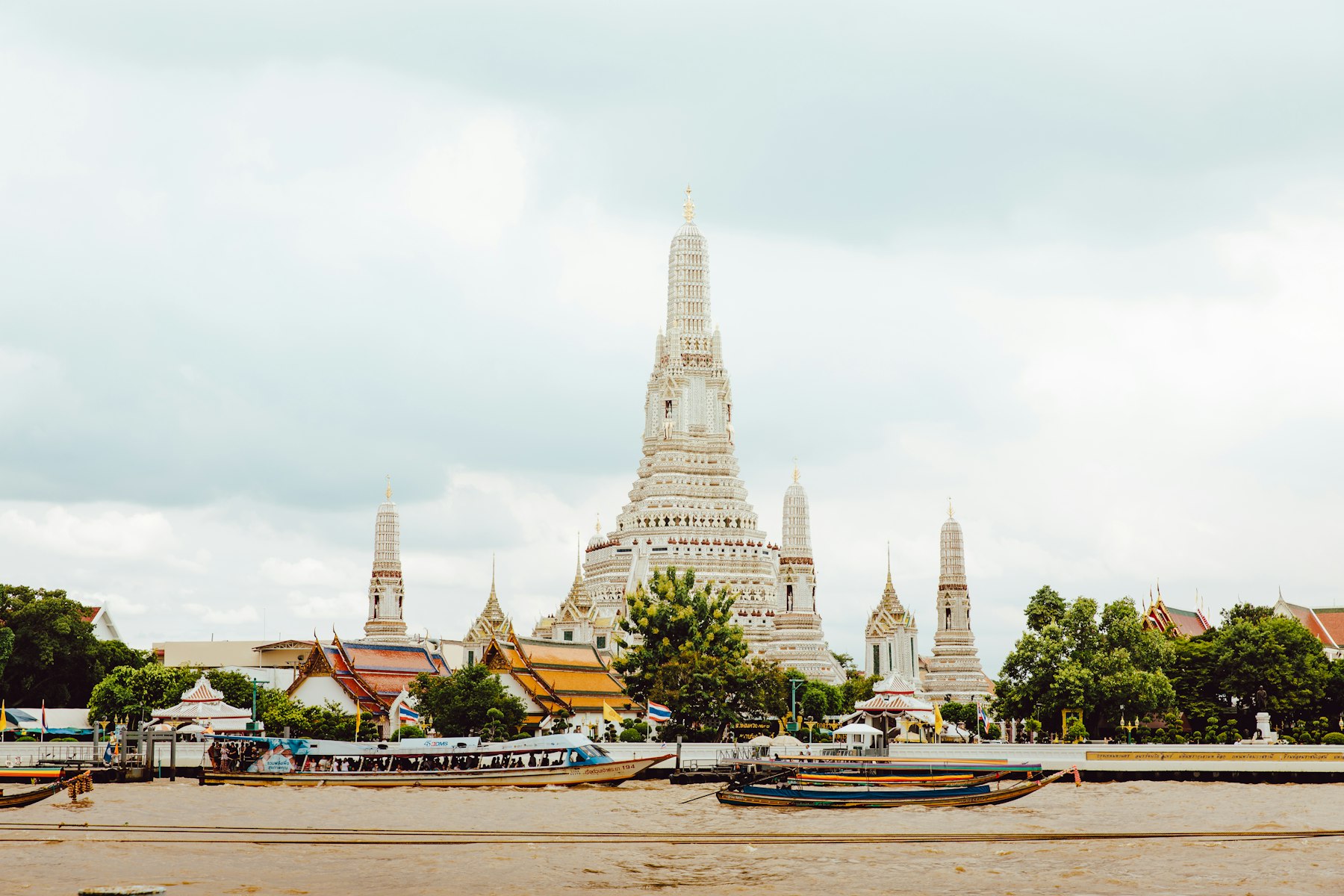 Wat Arun’s spires across the Chao Phraya River with longtail boats