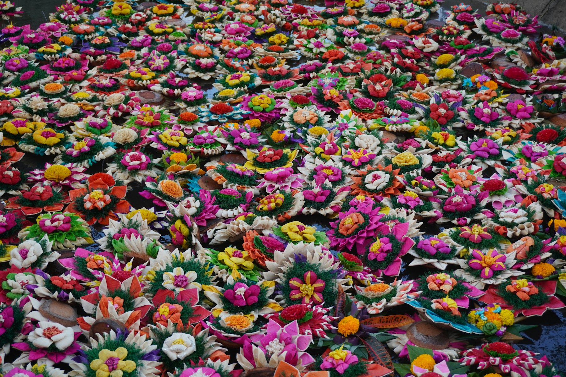 A dense field of brightly colored handmade Thai flower krathong crafts