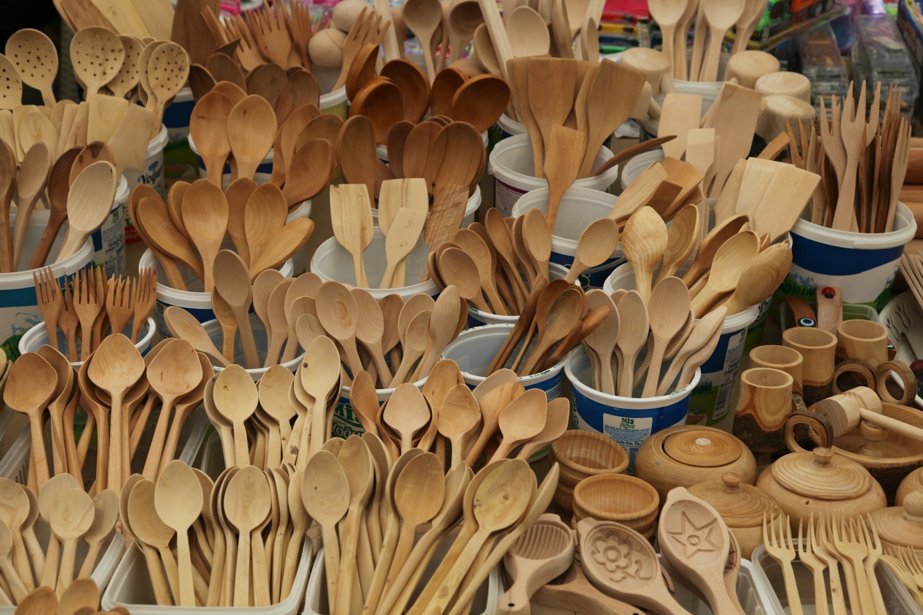Hand-carved teak spoons, spatulas and bowls piled on a market table