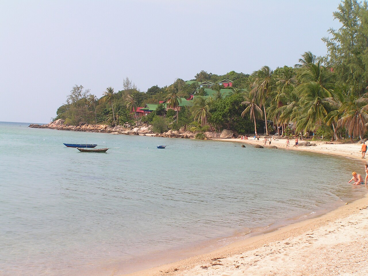 Wide shot: quiet cove on Phangan’s north coast, jungle to the waterline